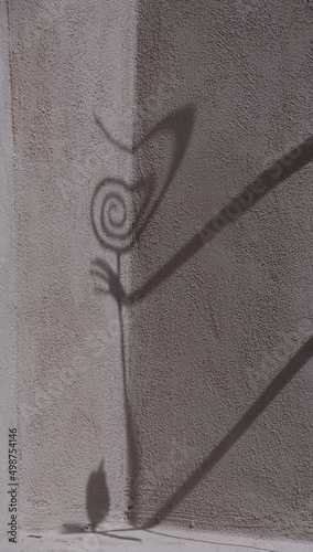 shadow of metal art on side of textured exterior wall of adobe style house shadow of art in Santa Fe new Mexico long arm reaching fir spiralled metal art afternoon light casting long shadows on wall  photo