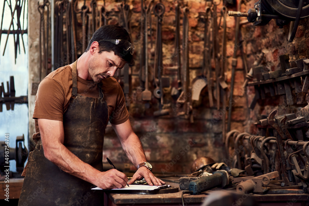 Always remember to go through your paperwork. Cropped shot of a handsome young craftsman filling out paperwork while working inside a metal workshop. Always remember to go through your paperwork. Cropped shot of a handsome young craftsman filling out paperwork while working inside a metal workshop.