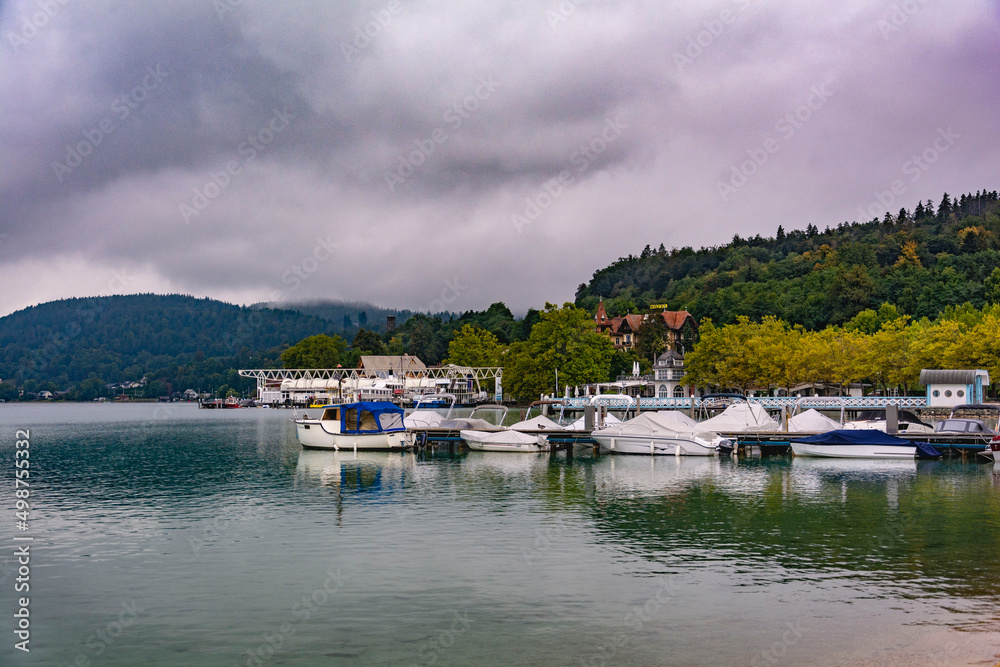 Austrian mountain pier with boats on a calm mirroring water in a cloudy autumn morning Austrian mountain pier with boats on a calm mirroring water in a cloudy autumn morning
