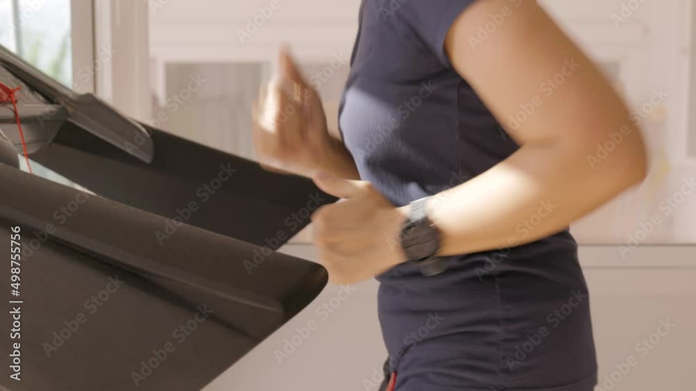 Woman athletic doing exercise on the treadmill. Walking at a fast pace for training for stamina and cardio at home during covid 19 pandemic.