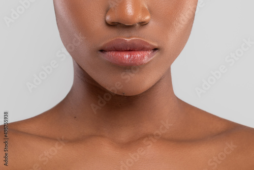 Serious sad pretty young african american woman with perfect skin and lips isolated on gray background, cropped