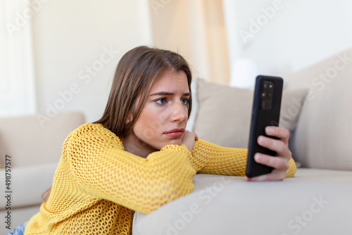 Valokuvatapetti Pensive sad young woman holding smartphone waiting sms or call from boyfriend