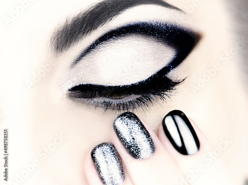 Beautiful female black and silver makeup and manicure. Female eye with black arrow.