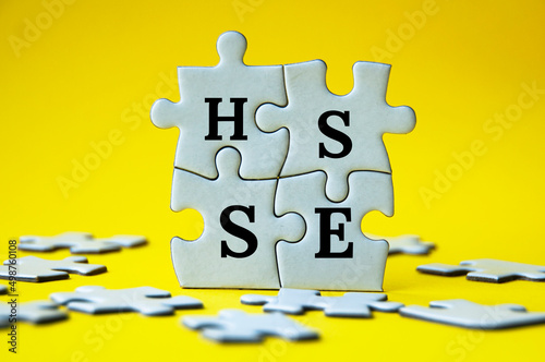 Short form text of HSSE on jigsaw puzzle with yellow background - Health, Safety, Security and Environment. Safety concept. photo