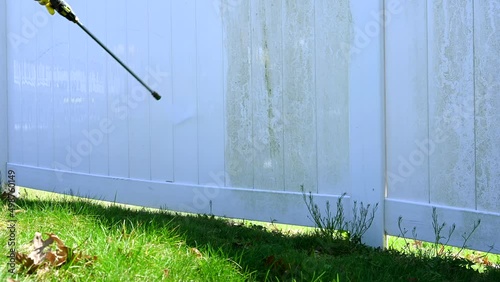 Close up of worker cleaning dirty white vinyl siding with high pressure power washer. professional cleaning services.