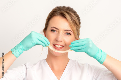 Young caucasian smiling female beautician holding wax for depilation over white background. Yellow sugar paste in hands master of depilation. Epilation concept