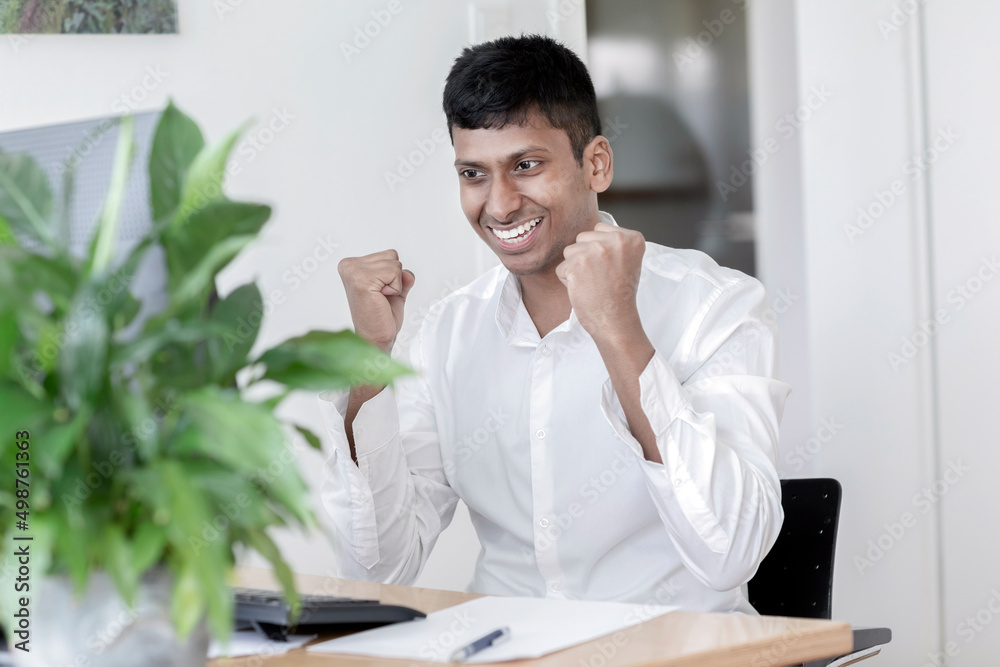 Junger Manager sitzt am Schreibtisch und ist begeistert Junger Manager sitzt am Schreibtisch und ist begeistert