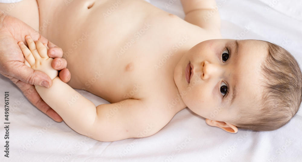 A woman, Masseur, is massaging the hands and chest of a baby boy. no clothes toddler on a table with white blanket. cute little child is very calm and relaxed, enjoying the massage. no tense muscles. A woman, Masseur, is massaging the hands and chest of a baby boy. no clothes toddler on a table with white blanket. cute little child is very calm and relaxed, enjoying the massage. no tense muscles.