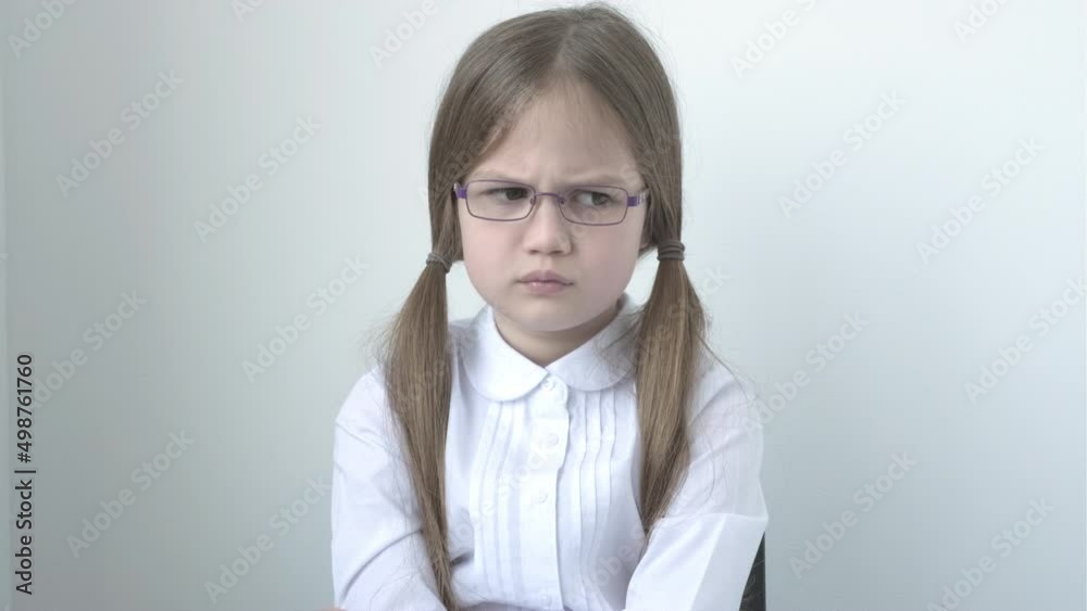 Portrait of sad schoolgirl in white blouse and glasses. Disappointed cute little girl feeling unhappy. Kid in uniform in negative mood. Education, bad grades, bullying. Back to school Portrait of sad schoolgirl in white blouse and glasses. Disappointed cute little girl feeling unhappy. Kid in uniform in negative mood. Education, bad grades, bullying. Back to school