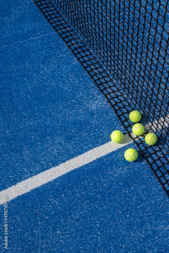 paddle tennis balls by the net on a blue paddle tennis court © Vic