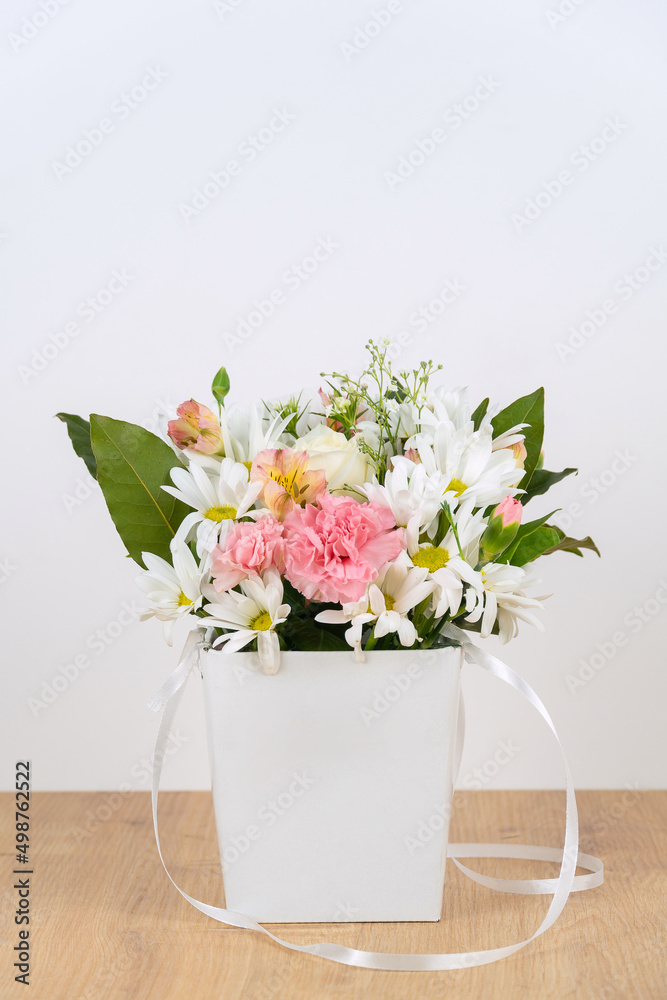 Beautiful composition of delicate flowers in a white gift box on the table on a neutral background. Gift for a holiday, Birthday, wedding, Mother's Day, Valentine's Day, Women's Day. Beautiful composition of delicate flowers in a white gift box on the table on a neutral background. Gift for a holiday, Birthday, wedding, Mother's Day, Valentine's Day, Women's Day.