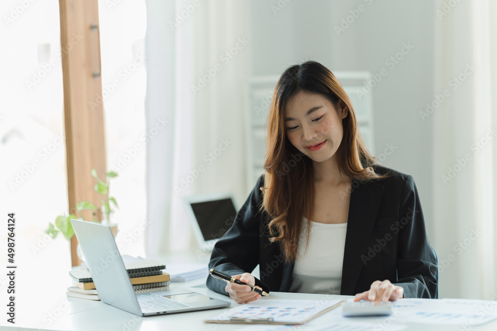 Portrait of Asian young female working on laptop and financial report at office. Portrait of Asian young female working on laptop and financial report at office.