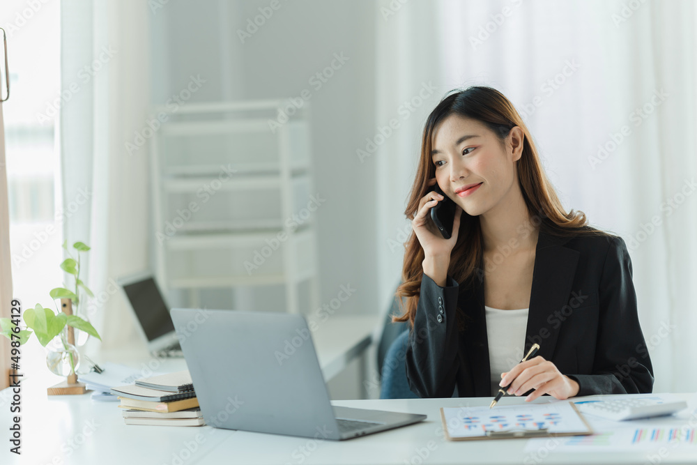 Asian business woman using smart phone and laptop in office. Asian business woman using smart phone and laptop in office.