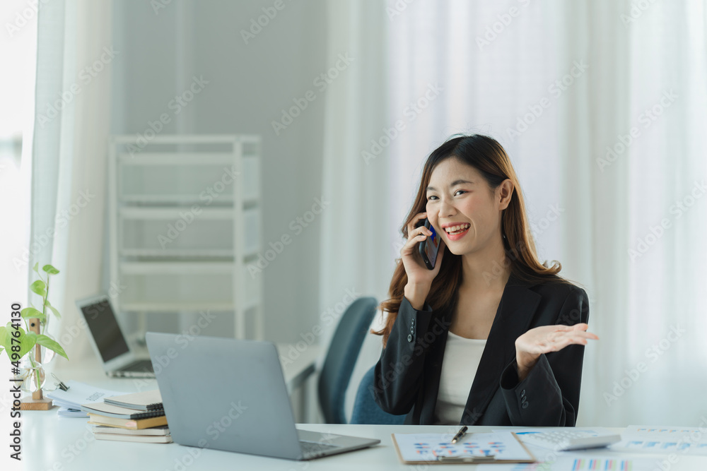 Asian business woman using smart phone and laptop in office. Asian business woman using smart phone and laptop in office.