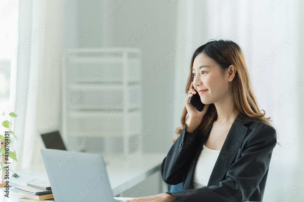 Asian business woman using smart phone and laptop in office. Asian business woman using smart phone and laptop in office.