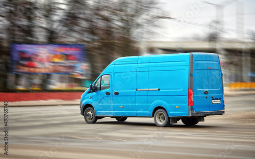 Delivery van speeding through city road. Express mail delivery, motion blur. Delivery van on city street, post deliver service. Courier deliver parcels and letters driving on road. Fast delivery truck