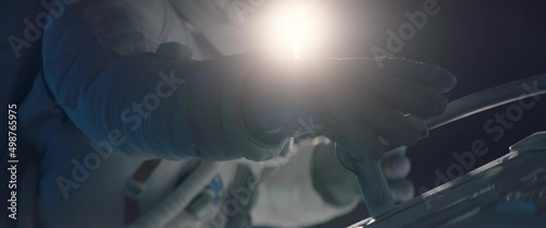 Female astronaut performing spacewalk, working on a outer part of a space craft. Shot with 2x anamorphic lens photo
