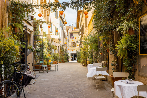 Beautifully landscaped narrow street with restaurant tables in the old town of Grosseto, in Maremma region of Italy. Cozy city view of the old Italian town