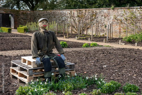 gardener scarecrow sitting on crates in the garden