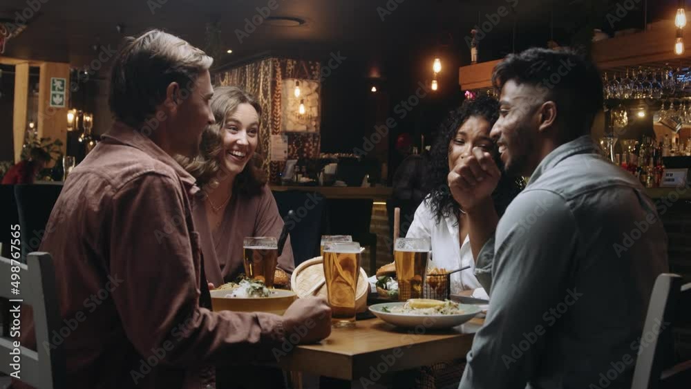 A multi-ethnic group of friends having dinner and beers at a restaurant and engaging in pleasant conversation A multi-ethnic group of friends having dinner and beers at a restaurant and engaging in pleasant conversation