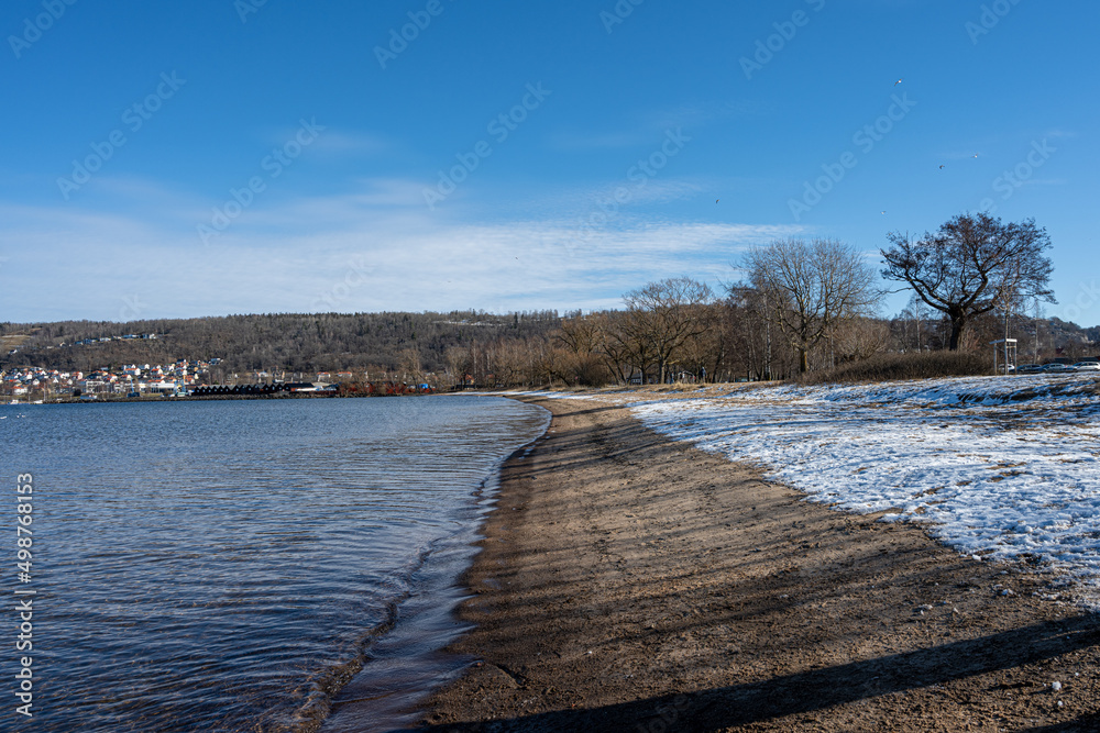 A winter beach covered with snow and a blue sky in the background