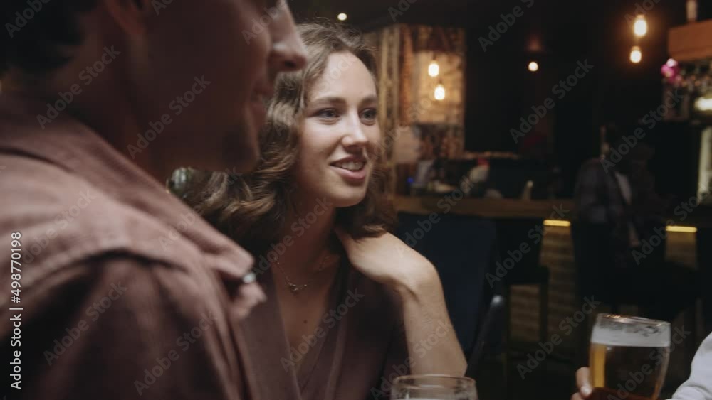 A multi-ethnic group of friends having beers at a restaurant, laughing and engaging in pleasant conversation. A multi-ethnic group of friends having beers at a restaurant, laughing and engaging in pleasant conversation.