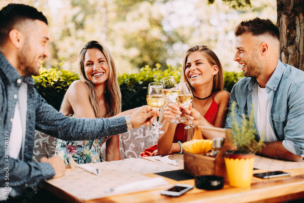 Group of Happy friends in the restaurant and toasting with glasses of wines Group of Happy friends in the restaurant and toasting with glasses of wines