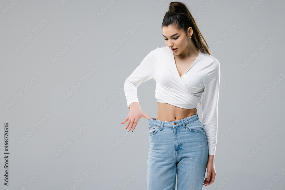 Young woman shows her flat stomach, quickly lost weight and jeans became her big