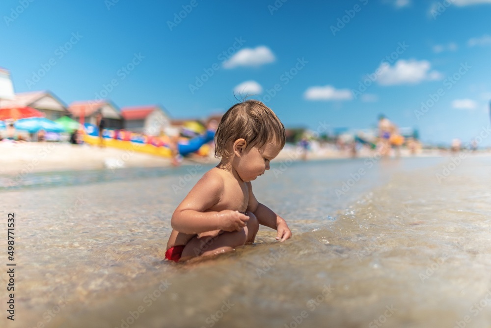 Kid collects shells and pebbles in the sea on a sandy bottom under the summer sun on a vacation Kid collects shells and pebbles in the sea on a sandy bottom under the summer sun on a vacation