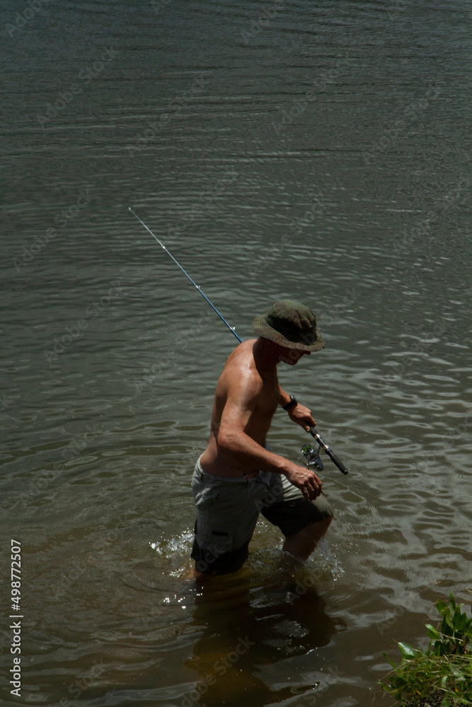 Outdoor activities. Hobbies and leisure. View of a man fishing in the lake shore. Outdoor activities. Hobbies and leisure. View of a man fishing in the lake shore.