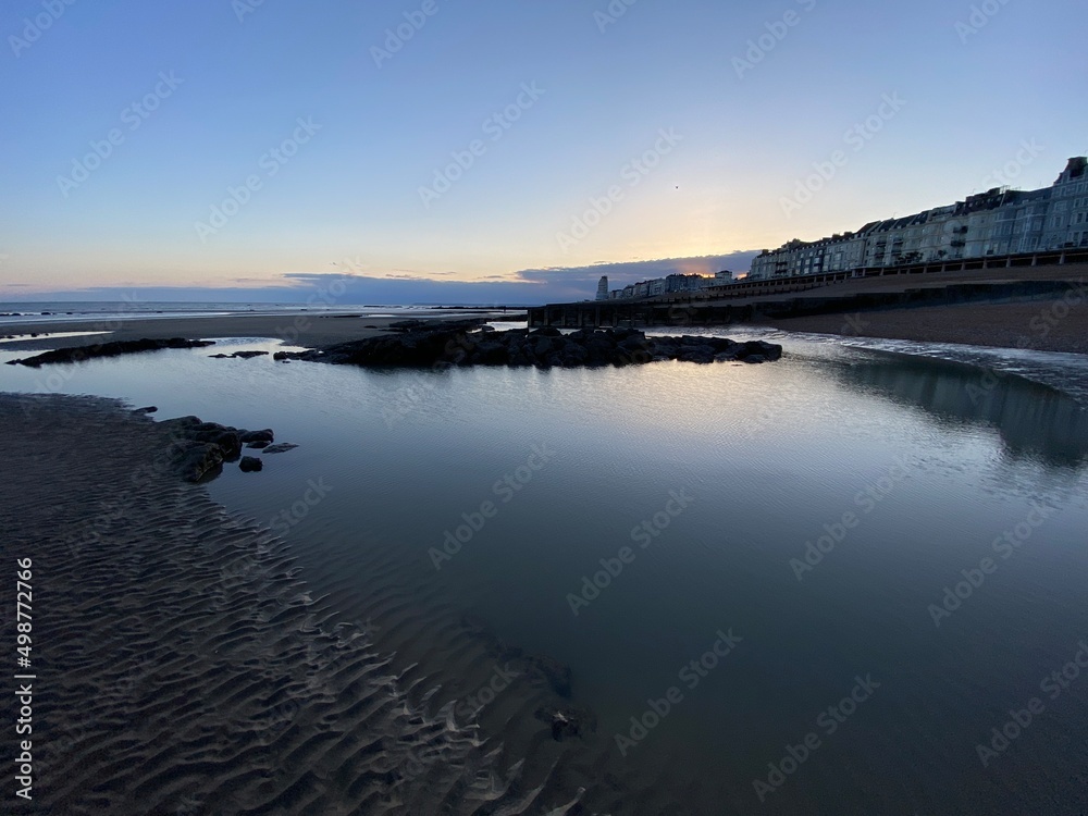 Hastings beach at low tide sea gone out, sunset reflecting on wet sand, Hastings, East Sussex, UK