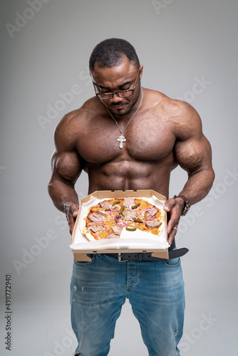 Quadro su tela Handsome strong man with muscular torso and pizza