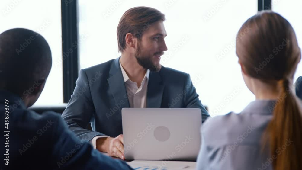 Caucasian young man in a suit talking with colleagues at a business meeting Caucasian young man in a suit talking with colleagues at a business meeting
