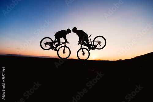 silhouette and frenzy of two cyclists showing off