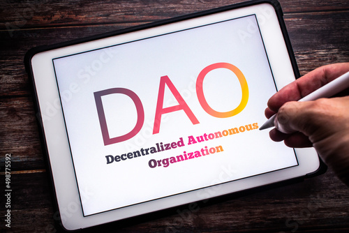 Fototapet The sign of DAO (Decentralized Autonomous Organization),  an organization represented by rules encoded as a transparent computer program, on tablet on wooden table