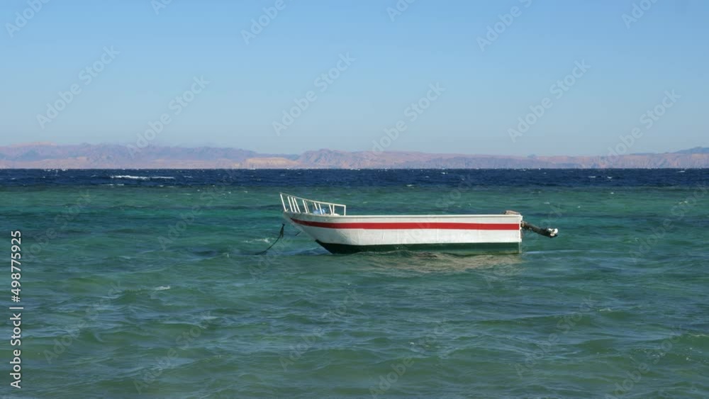 Empty white motorboat is rocking on Red sea waves. Fishing boat swaying on ripple water surface in windy day. Motor ship, outboard runabout floating near seaside. Travel, tourism, fishery Empty white motorboat is rocking on Red sea waves. Fishing boat swaying on ripple water surface in windy day. Motor ship, outboard runabout floating near seaside. Travel, tourism, fishery