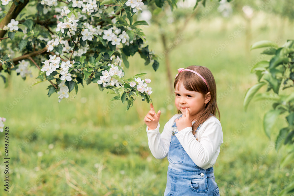 Portrait of a girl in a spring garden near blooming apple trees
