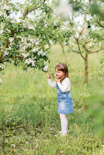 little girl in a spring garden near blooming apple trees
