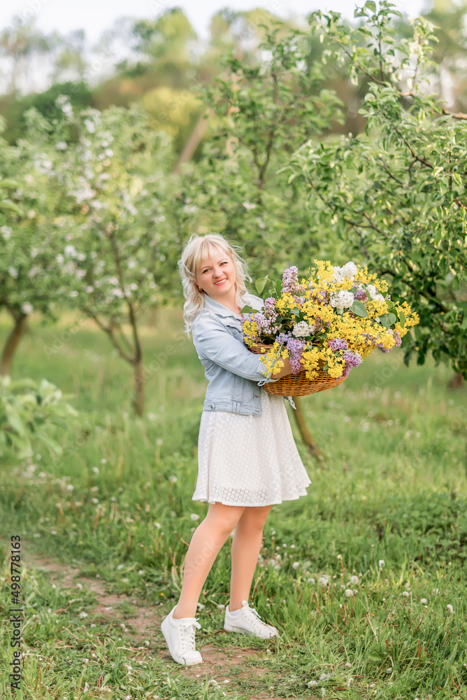 young blonde woman with a large basket of flowers in the spring garden young blonde woman with a large basket of flowers in the spring garden