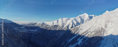 Scenic panorama of winter landscape in the Fagaras mountains,Transfagarasan, Romania in winter covered by snow in a very beautiful sunny day of winter with blue sky and few clouds.