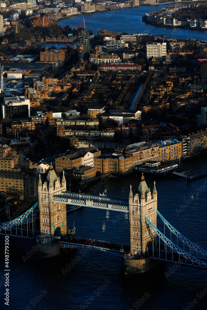 London view with the most iconic symbol of London, Tower Bridge illuminated by the last rays of the sun before sunset and  skyline buildings in Canary Warf, view from The Shard observation deck tower.