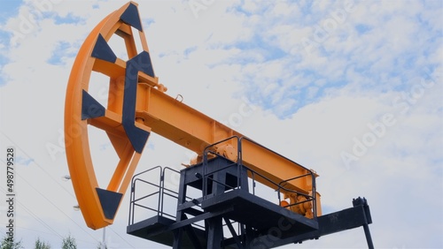 Modern oil rocking chair in a field of green grass. The concept of the cost of a barrel of oil, oil production and processing of raw materials.