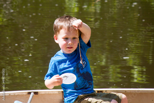 The first fishing trip cute young boy looking studying smiling at his entire worm nightcrawler showing the emotions of pride excitement challenge and amazement. photo