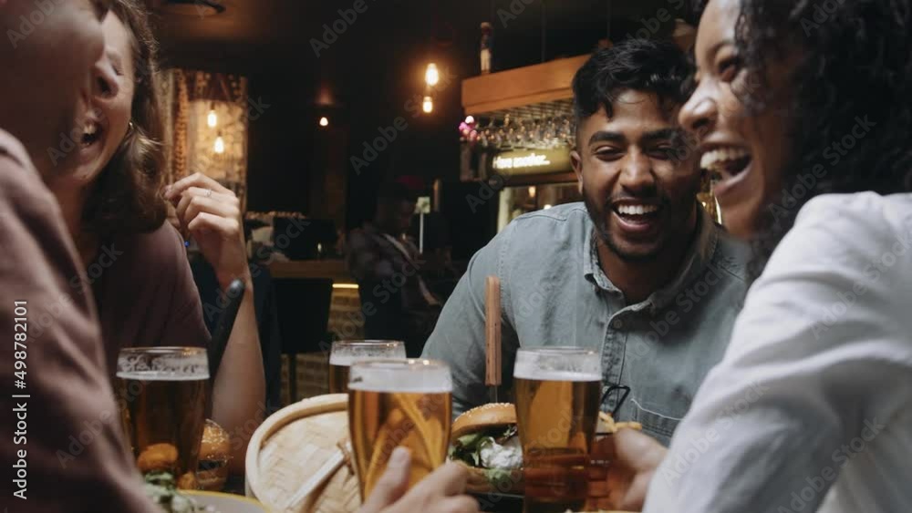 A multi-ethnic group of friends having dinner and beers at a restaurant and engaging in pleasant conversation A multi-ethnic group of friends having dinner and beers at a restaurant and engaging in pleasant conversation