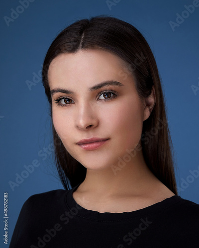 portrait of a young brunette lady on a dark blue background.