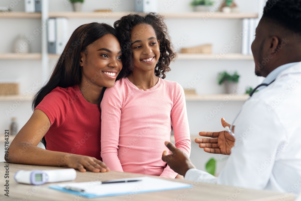 Happy african american mother and daughter having appointment with pediatrician