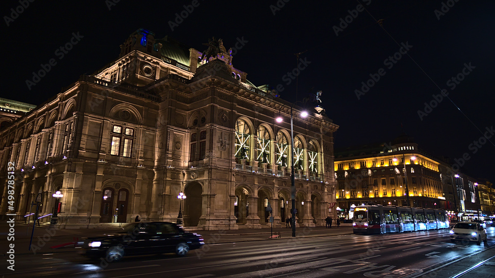 Front view of the main entrance of famous Vienna State Opera house, Austria, in the historic downtown with illuminated stone facade. Blurred motion.