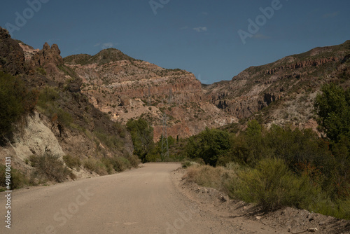 Travel. View of the dirt road across the arid desert and colorful rock formations. 
