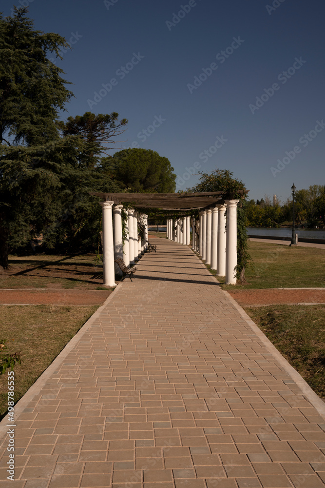 General San Martín park in a sunny day. View of the walkway, plants and decorative white columns.