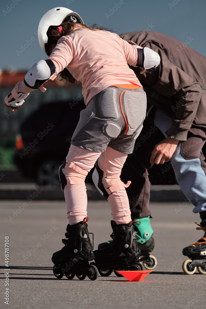 Fototapeta premium The coach teaches a young girl to roller skate. Individual lessons with a trainer.